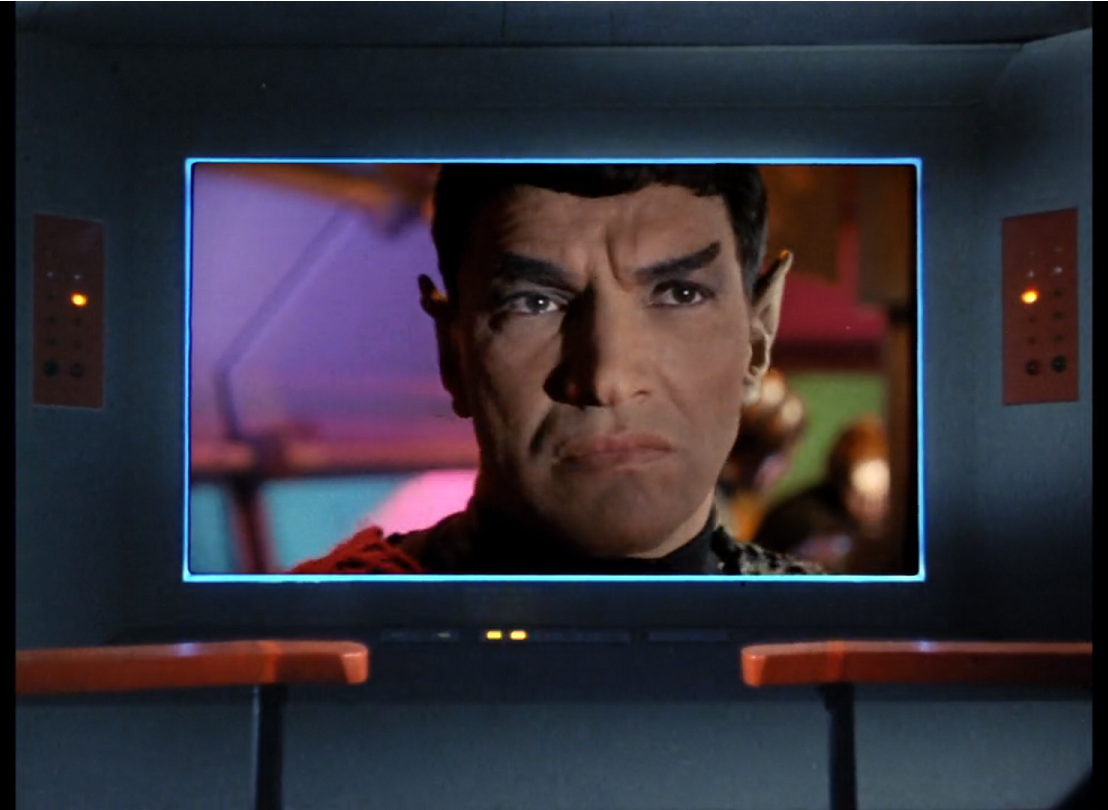 The bridge screen of the Enterprise, showing a headshot of a white man with dark hair and pointed ears and slanted eyebrows similar to Spock’s.