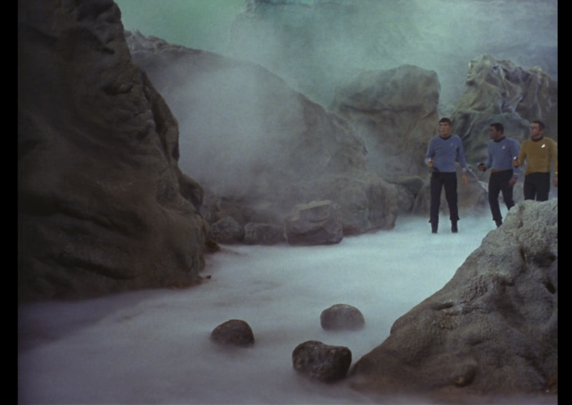 Spock, Boma and Gaetano approaching cautiously through the ravine, the floor of which is blanketed with white vapor.